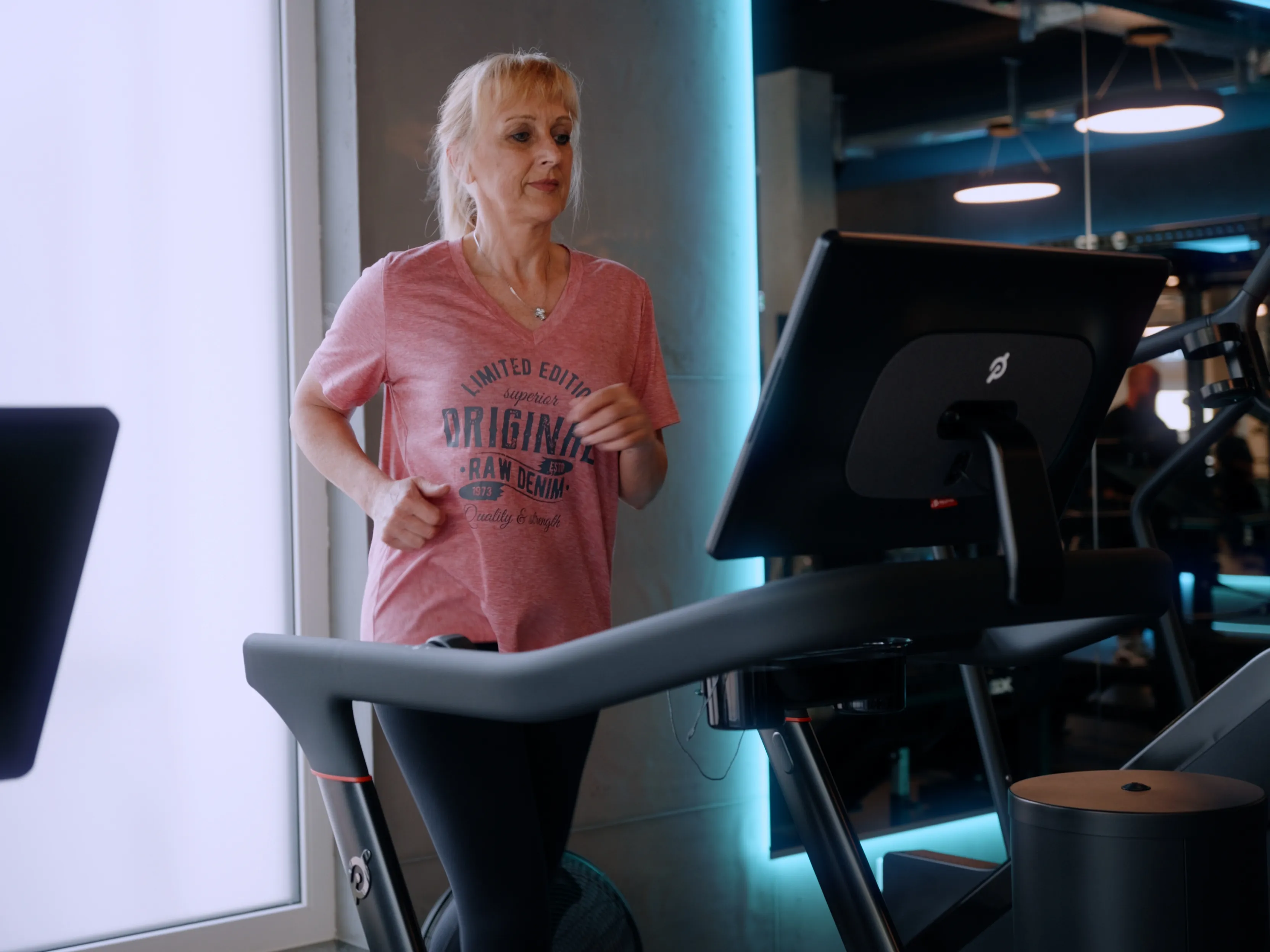 Frau läuft auf einem Laufband in einem modernen Fitnessstudio mit LED-Beleuchtung.